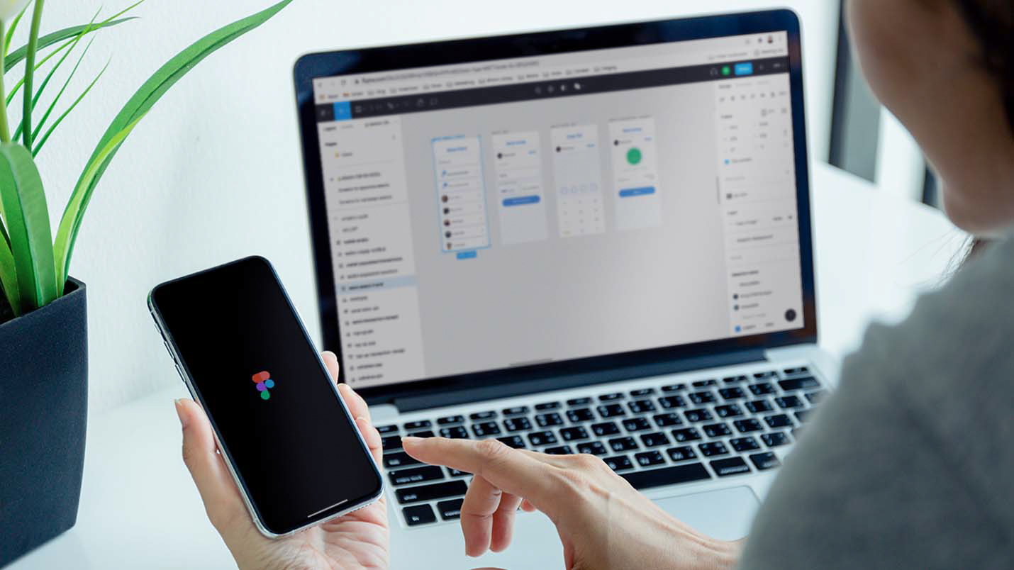 A person looking at a phone and laptop screen, both displaying Figma on its screens