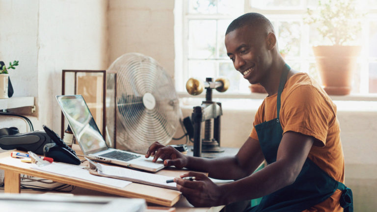 a smiling man seated at his workstation using online tools