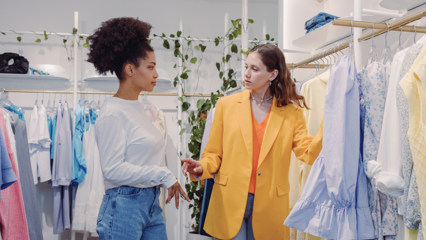 two women in a clothing store browsing clothing items