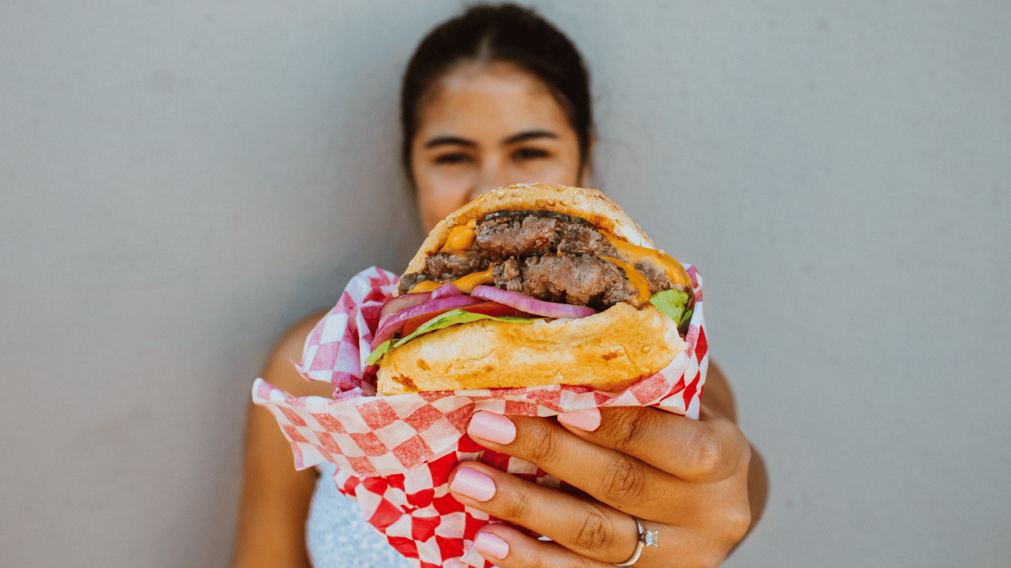 a person holding up a beef burger from Dope Burger Co.