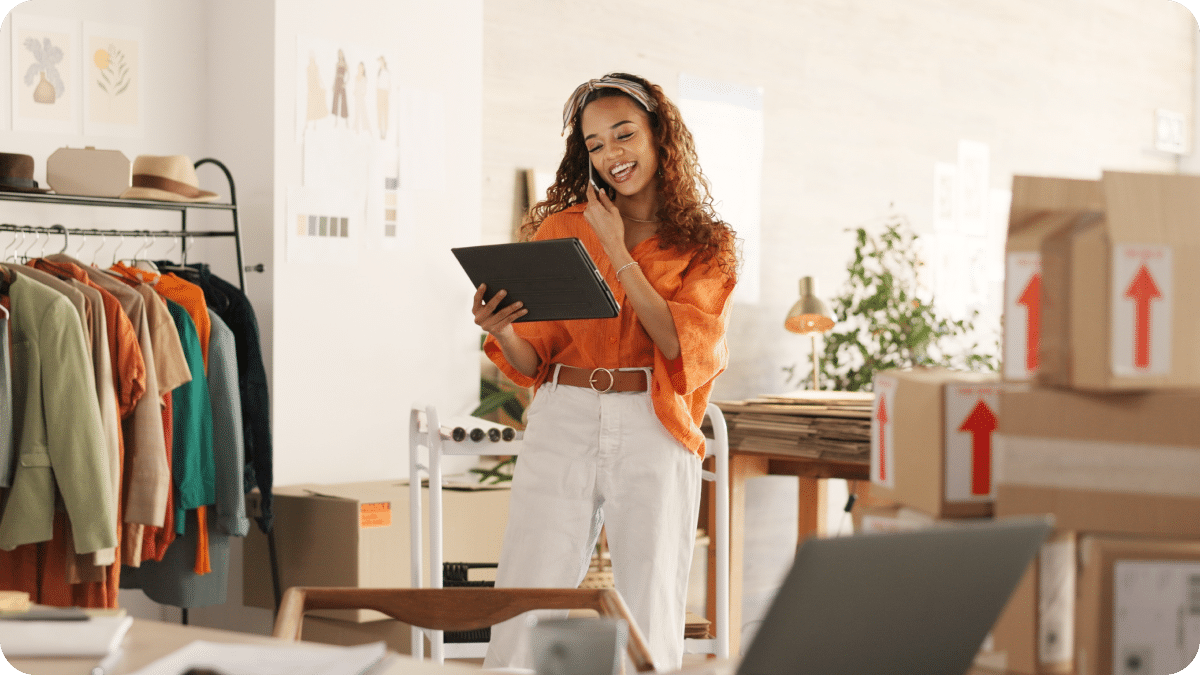 A business owner standing in her office talking on the phone while using a digital business tool on her iPad